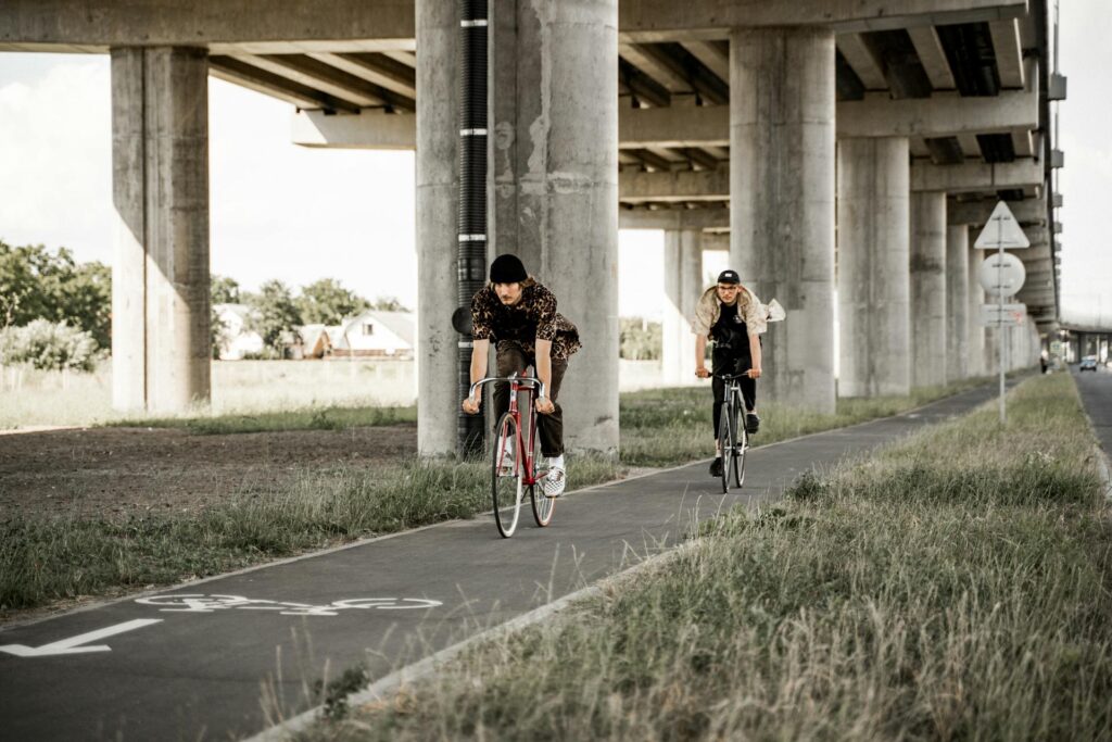 two people riding on a bike lane under bridge